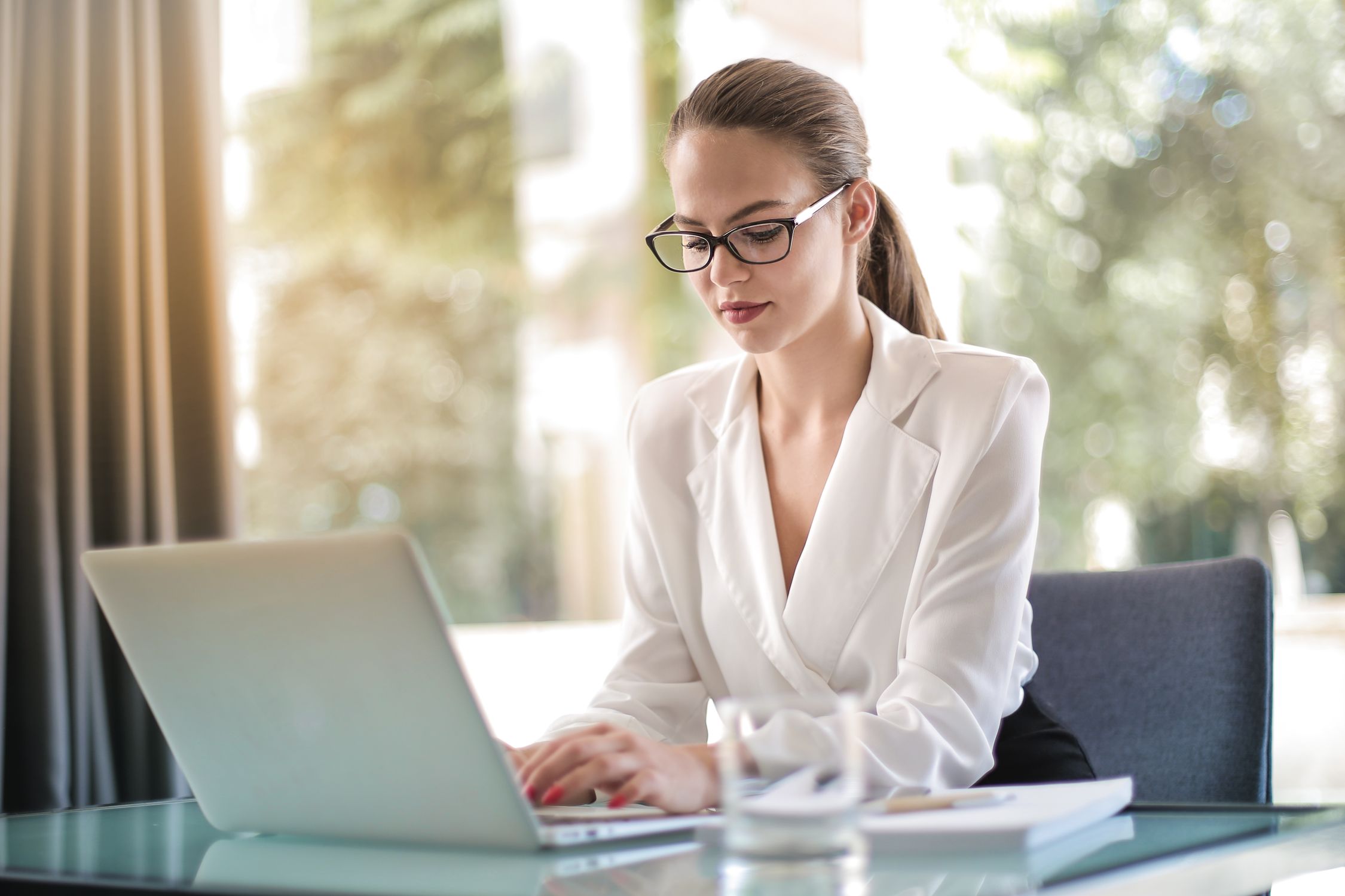 Emprendedora concentrada escribiendo en laptop en su espacio de trabajo, desarrollando su presencia digital