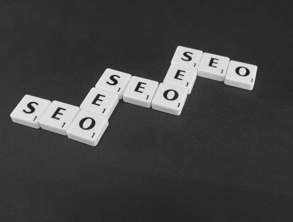 Letras de scrabble deletreando SEO sobre superficie negra, representando posicionamiento en buscadores