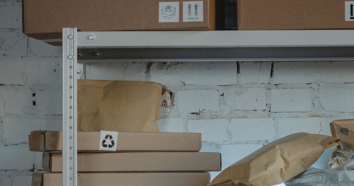 Cajas de cartón apiladas con etiquetas de frágil en estantes industriales de un almacén de e-commerce
